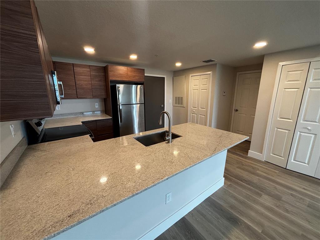 A kitchen features a granite island, stainless steel appliances, and dark wood cabinetry — 4424 S TEXAS AVENUE UNIT 304, ORLANDO, FL