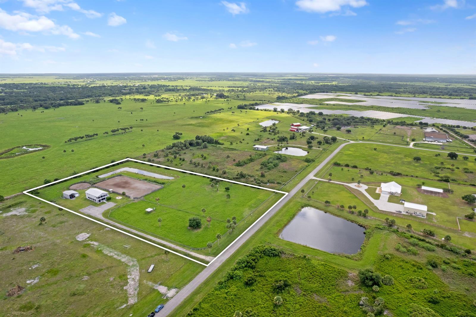 An aerial view shows a fenced rural property featuring a house, barn, and riding arena — 6536 SE 26th Trail, Okeechobee FL 34974, OKEECHOBEE, FL