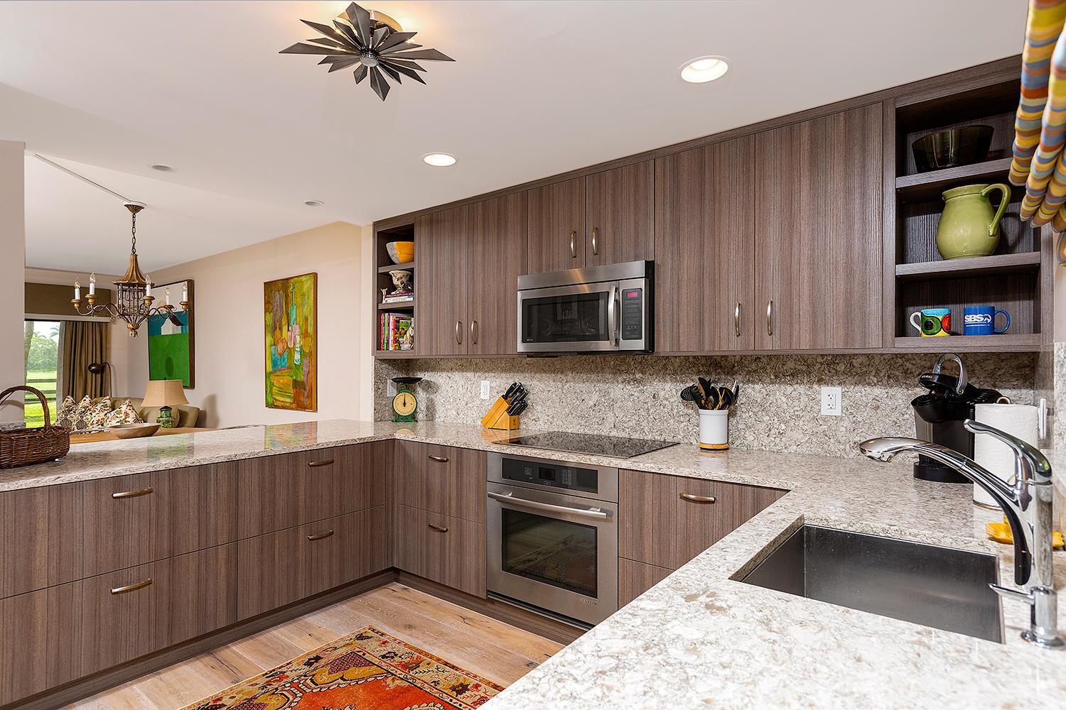 A modern kitchen features wood-grain cabinets, granite countertops, stainless steel appliances, and an open layout — 11397 Pond View Drive # E102, Wellington FL 33414, WELLINGTON, FL