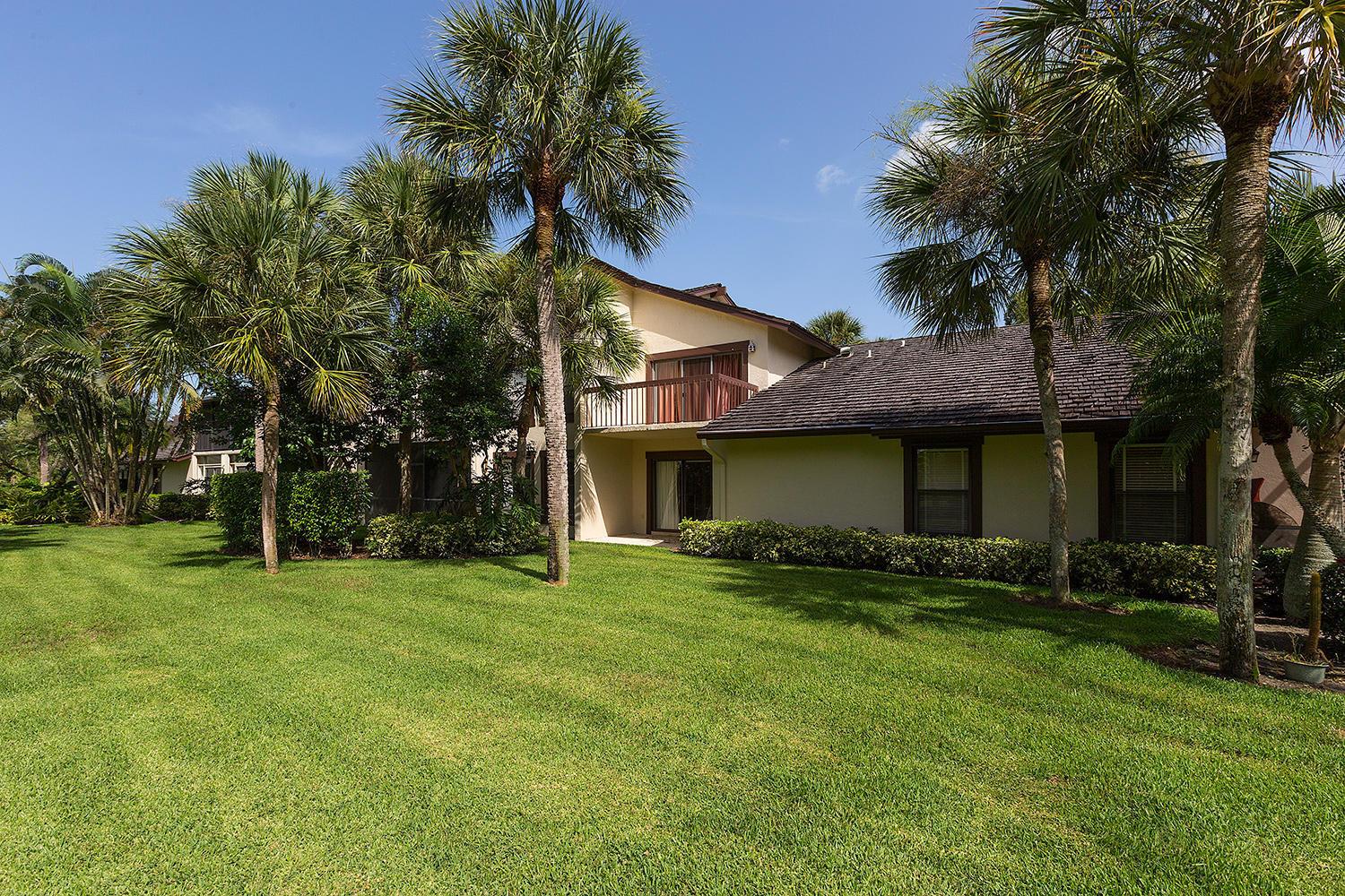 A two-story residential building with a balcony and palm trees on a grassy lawn — 11397 Pond View Drive # E102, Wellington FL 33414, WELLINGTON, FL