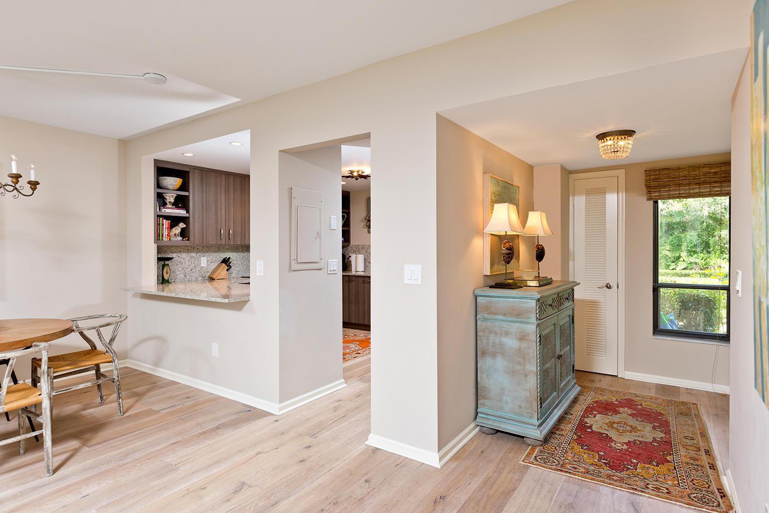 A dining area and entryway feature light wood floors, a pass-through kitchen, and a cabinet — 11397 Pond View Drive # E102, Wellington FL 33414, WELLINGTON, FL