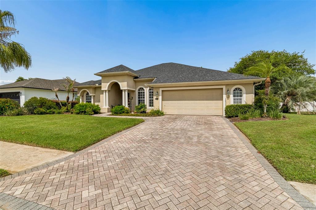 A single-story house with a beige stucco exterior, a dark shingled roof, and a paved driveway — 2349 CHESTERFIELD CIRCLE, LAKELAND, FL