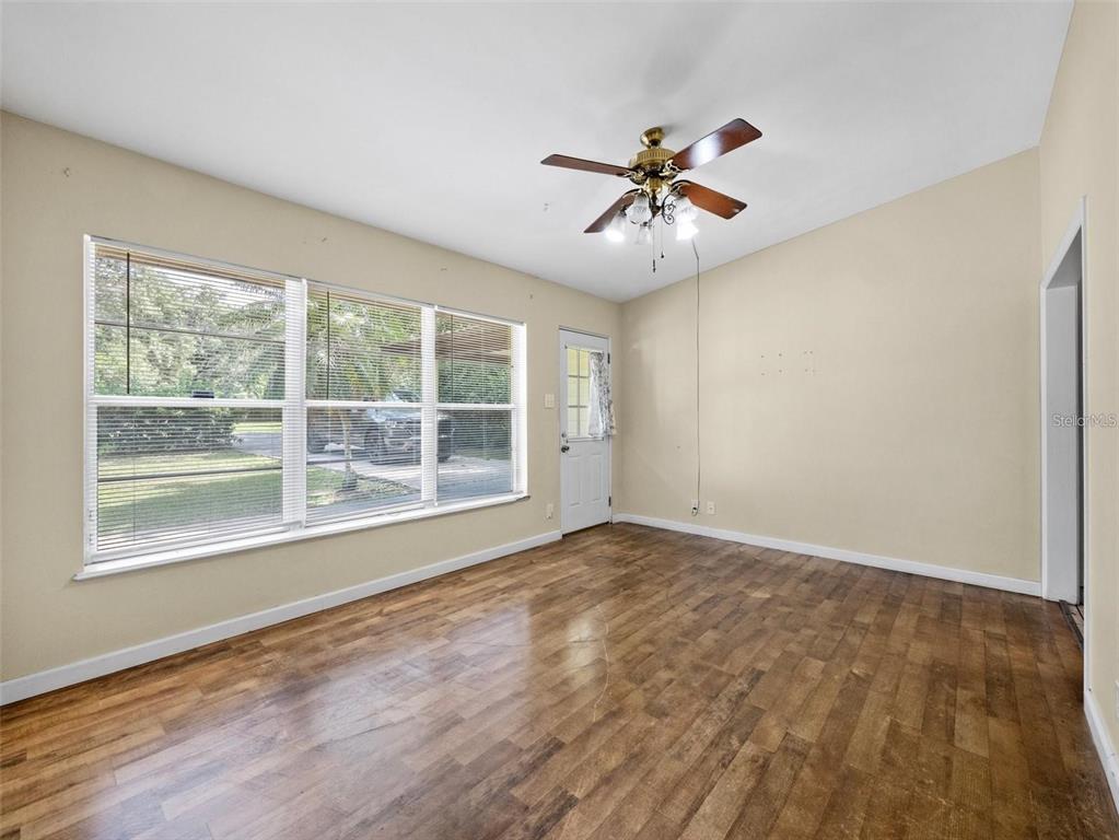 An empty room features wood-look flooring, a ceiling fan, and a large window — 25519 COLMAR AVENUE, SORRENTO, FL