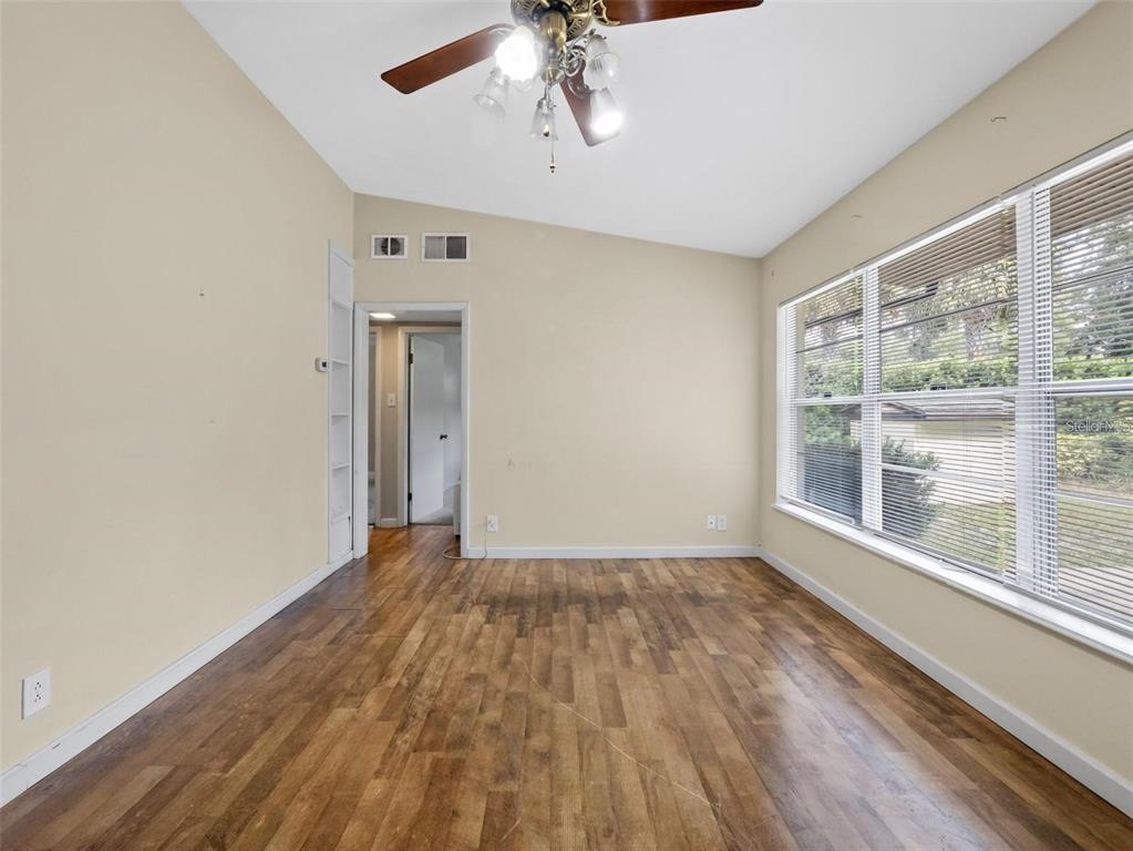 An empty room with wood-look flooring, a ceiling fan, and a large window with blinds — 25519 COLMAR AVENUE, SORRENTO, FL