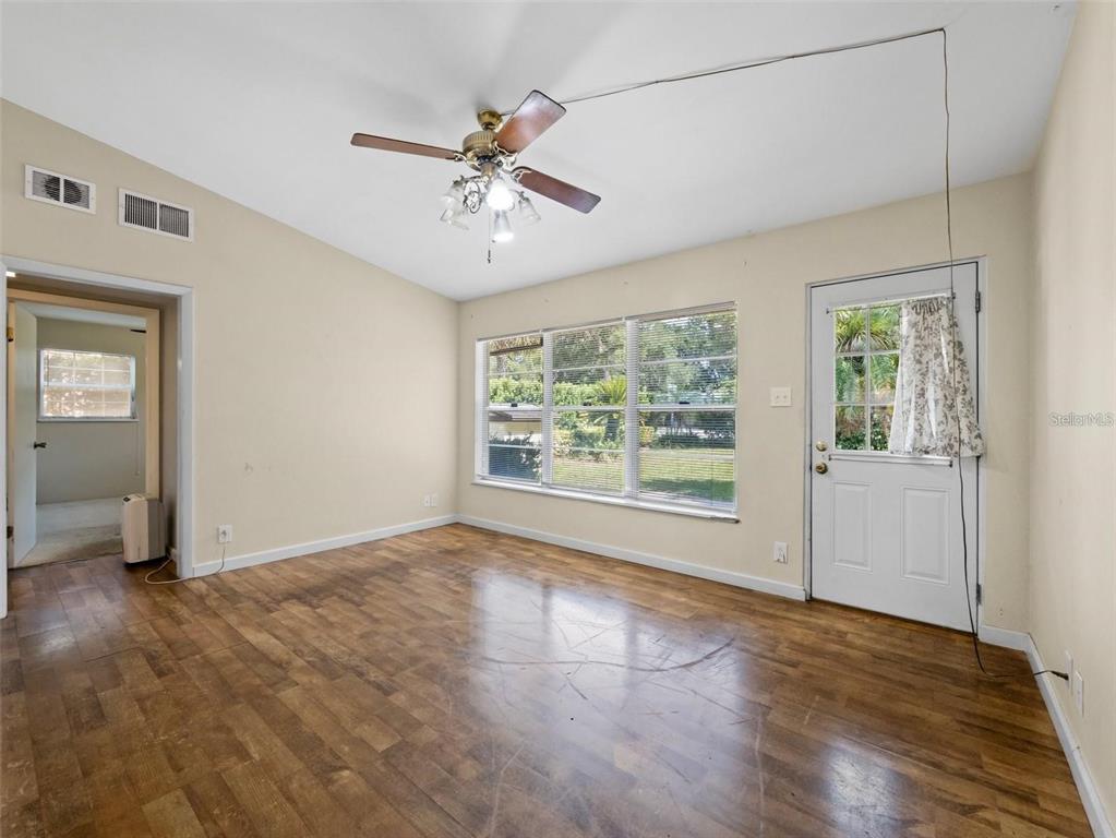 A room with wood-look flooring, a ceiling fan, large windows, and a white exterior door — 25519 COLMAR AVENUE, SORRENTO, FL