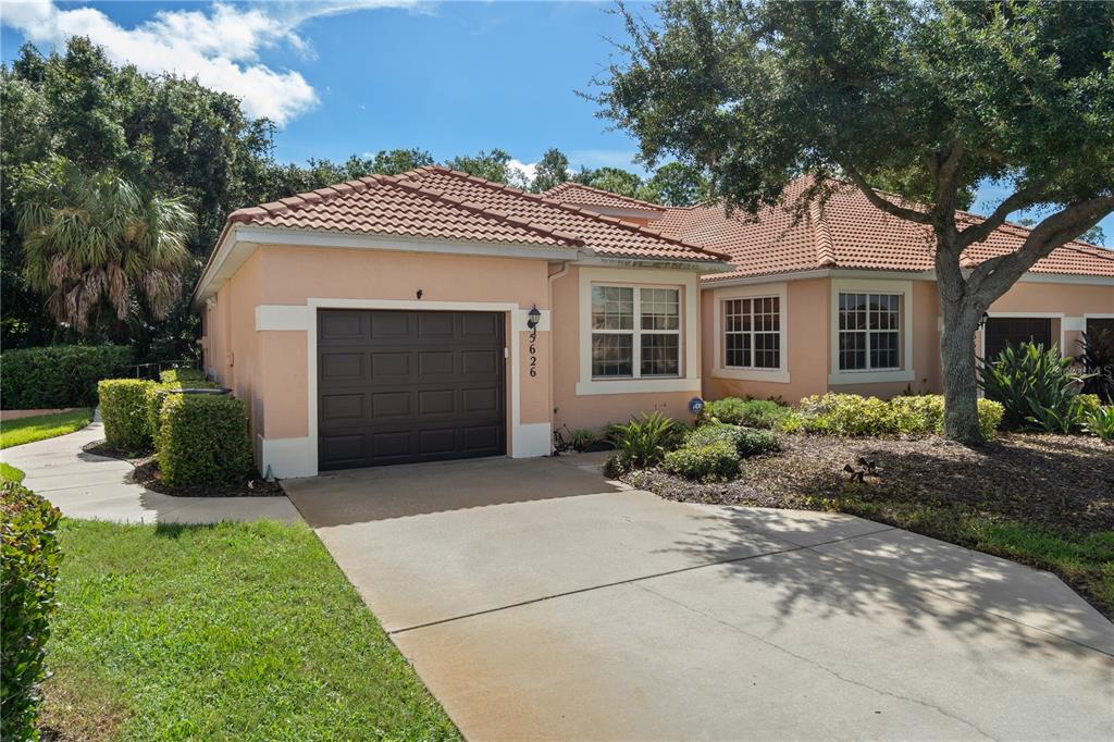 A single-story house with a peach exterior, a brown garage door, and a tiled roof — 5626 CORTINA LANE, PALMETTO, FL