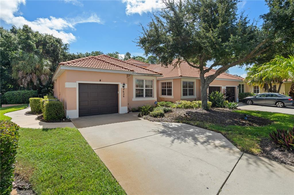 A single-story peach-colored house with a tile roof, a garage, and a concrete driveway — 5626 CORTINA LANE, PALMETTO, FL