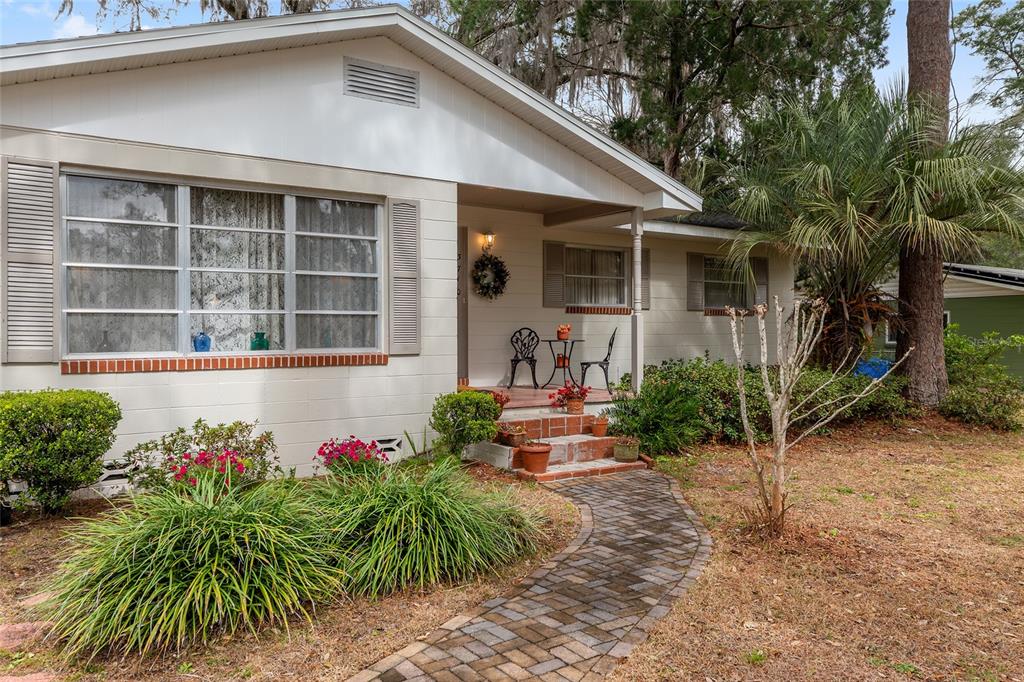 A single-story house with a brick walkway, front porch, and landscaping under a large tree — 3710 NW 22ND PLACE, GAINESVILLE, FL