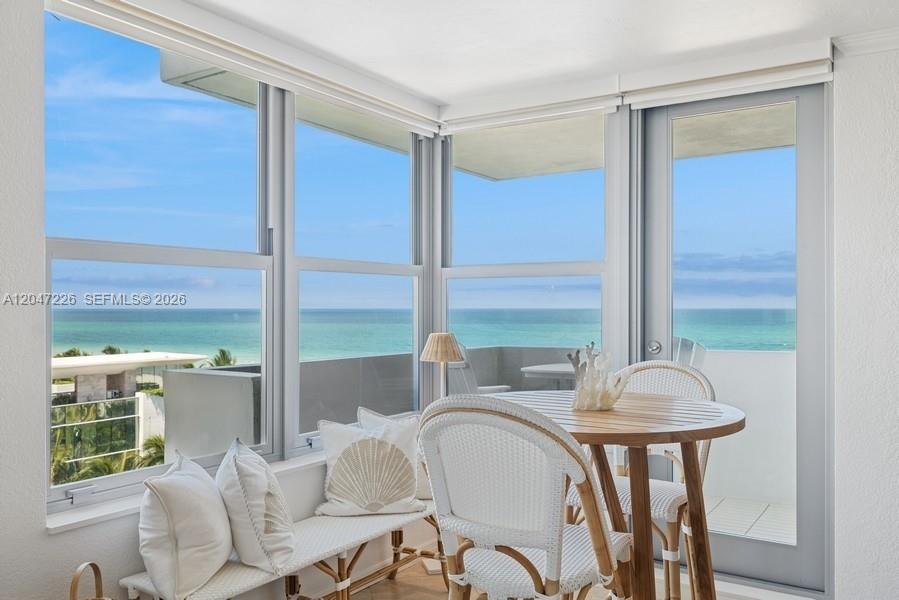 A sunroom features a dining set, bench seating, and expansive windows overlooking the ocean — 2899 Collins Ave # 1025, Miami Beach FL 33140, MIAMI BEACH, FL