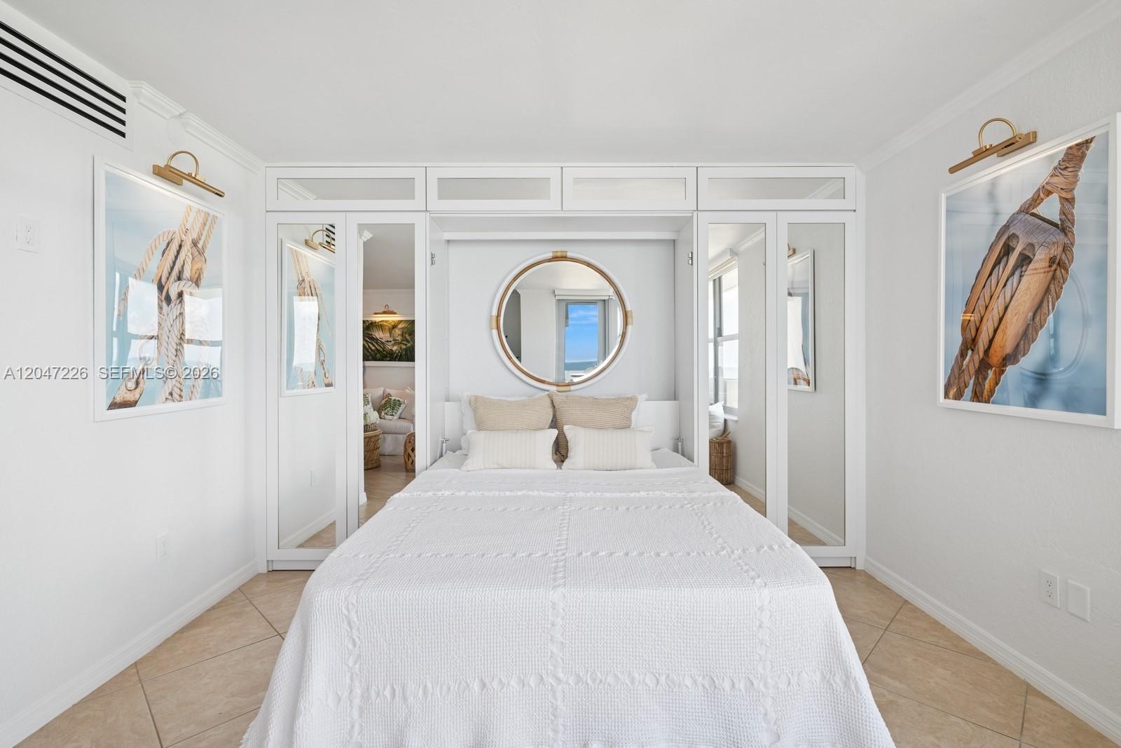 A bedroom features a white Murphy bed, mirrored closet doors, and nautical wall art — 2899 Collins Ave # 1025, Miami Beach FL 33140, MIAMI BEACH, FL