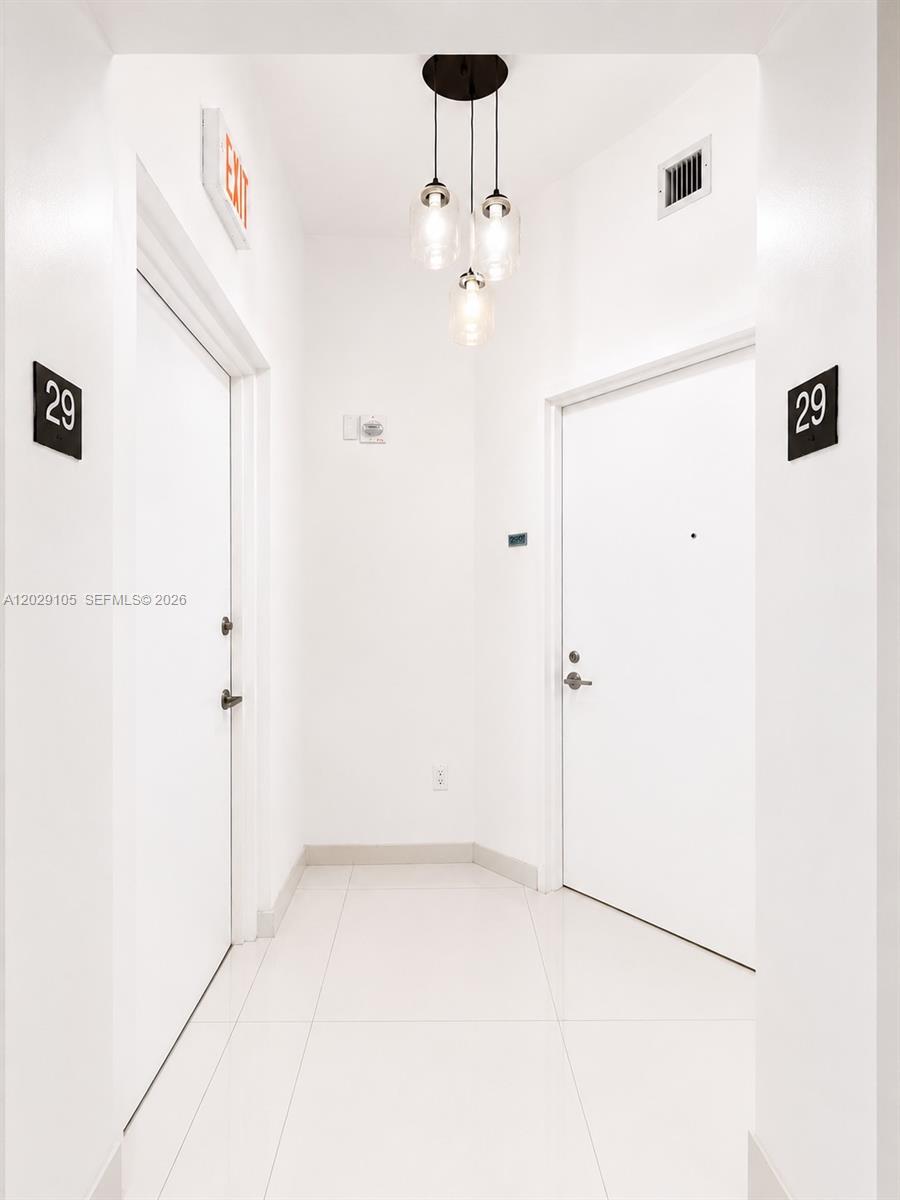 A hallway with white walls, tile flooring, two doors labeled 29, and a pendant light — 2020 N Bayshore Dr # 2909, Miami FL 33137, MIAMI, FL