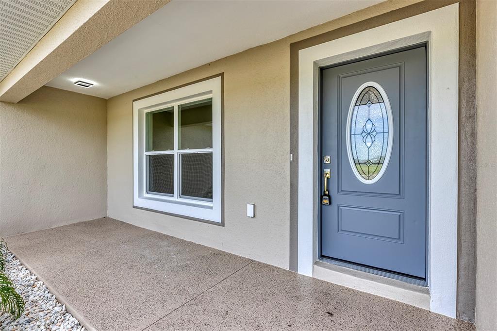 A gray front door with an oval glass insert sits next to a white-framed window — 10463 SW 140TH AVENUE, DUNNELLON, FL