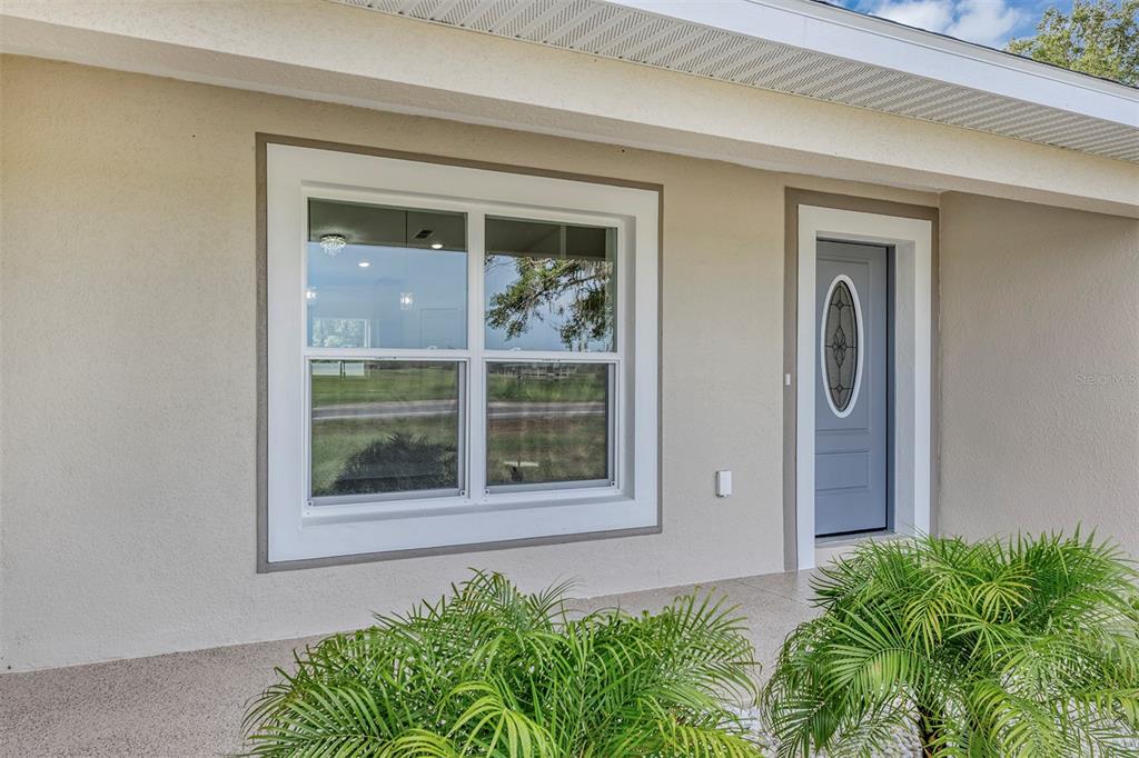 A light-colored house exterior features a gray front door and a large white-framed window — 10463 SW 140TH AVENUE, DUNNELLON, FL