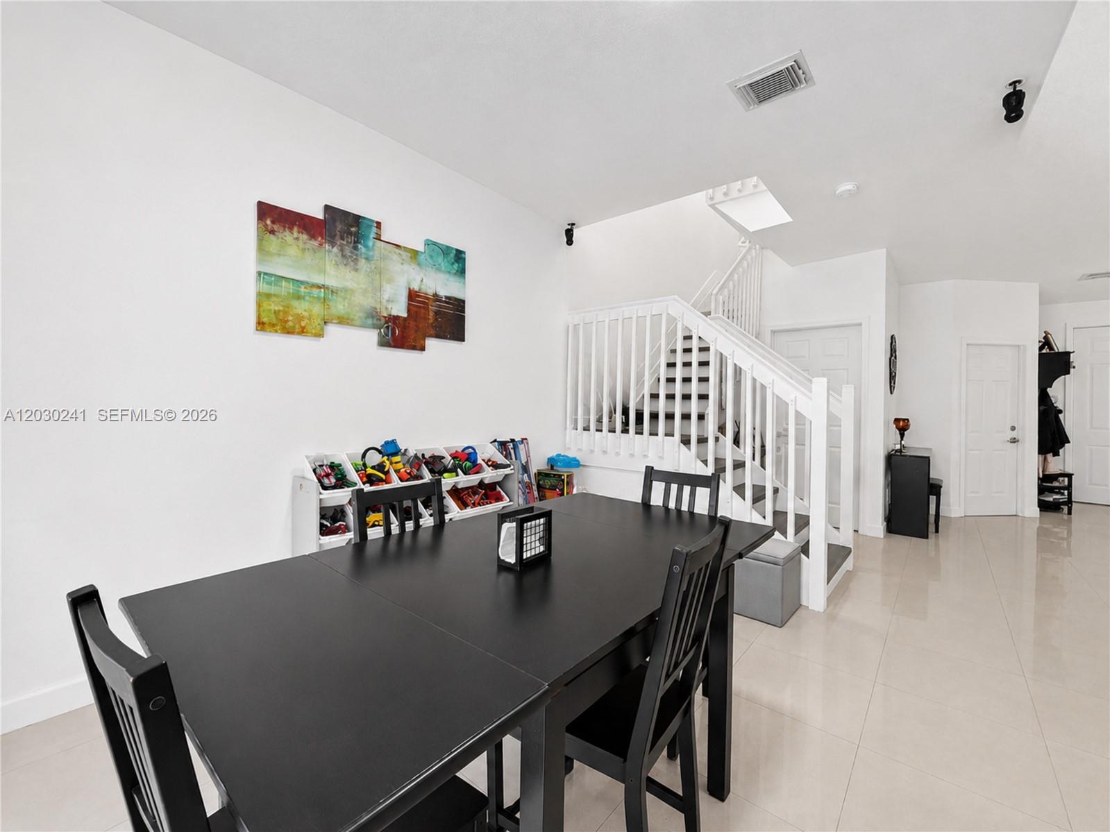 A dining area features a black table and chairs, a toy organizer, and a staircase — 10918 NW 78th Ter, Doral FL 33178, DORAL, FL