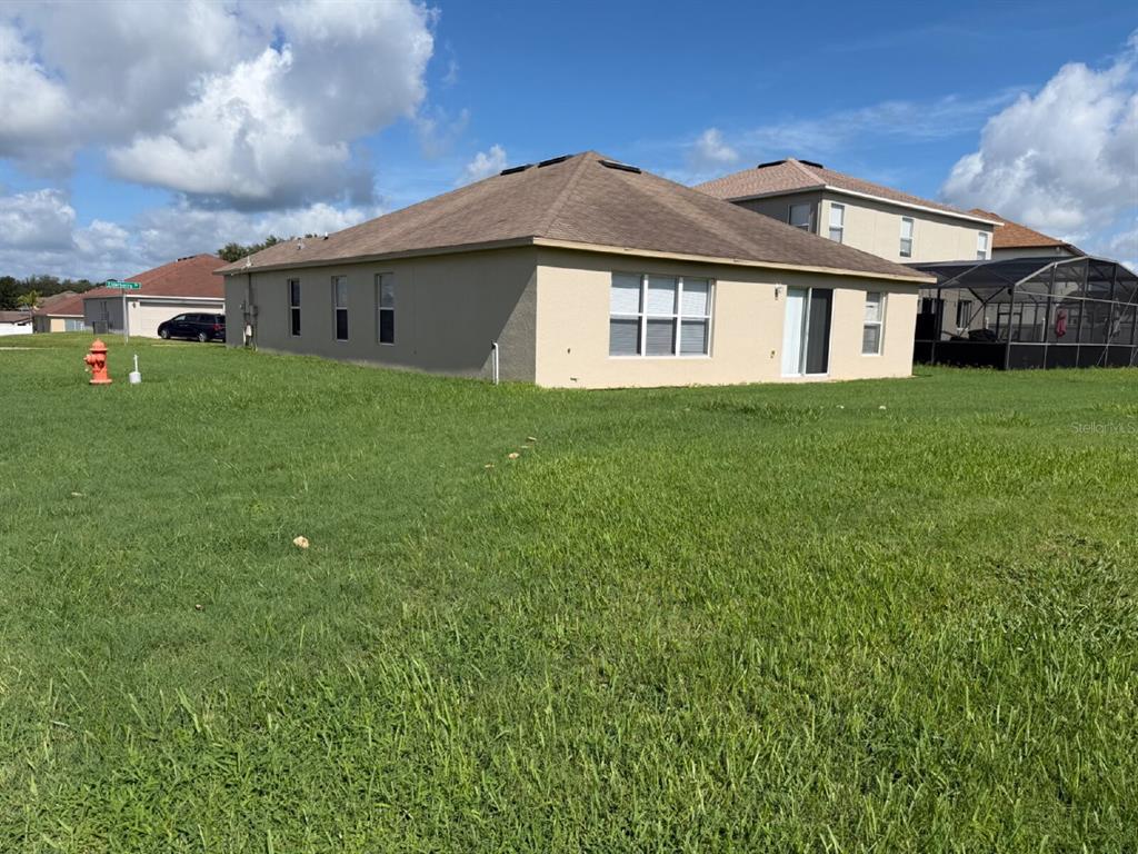 A view of the side and rear exterior of a single-story house with a lawn — 1153 ELDERBERRY DRIVE, DAVENPORT, FL
