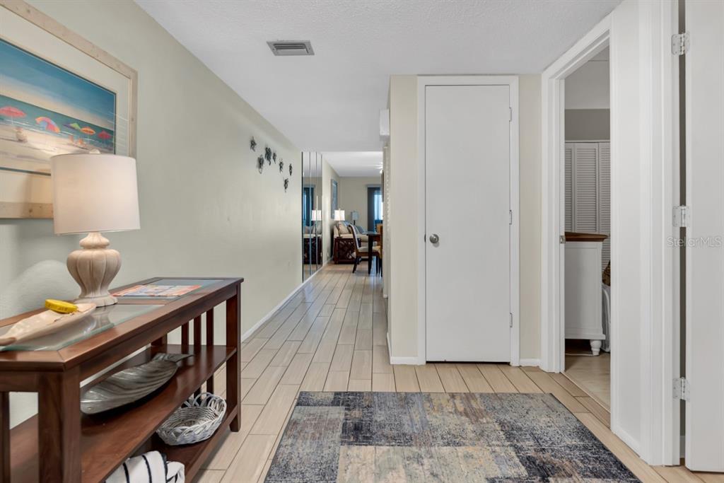 A hallway with tile flooring leads to a living area, featuring a console table nearby — 2312 GULF DRIVE N UNIT 103, BRADENTON BEACH, FL