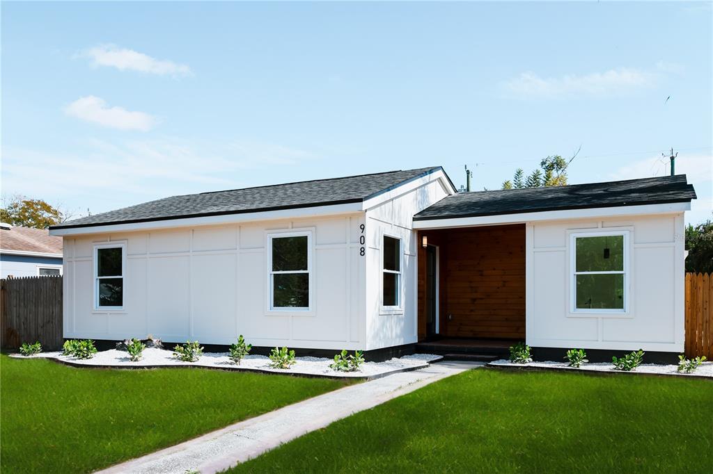 A white, single-story house features a wood-paneled entryway and a white gravel garden bed — 908 61ST STREET S, GULFPORT, FL