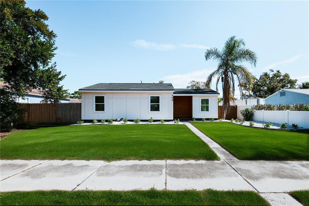 A single-story white house with a wood-accented entryway and a manicured front lawn — 908 61ST STREET S, GULFPORT, FL