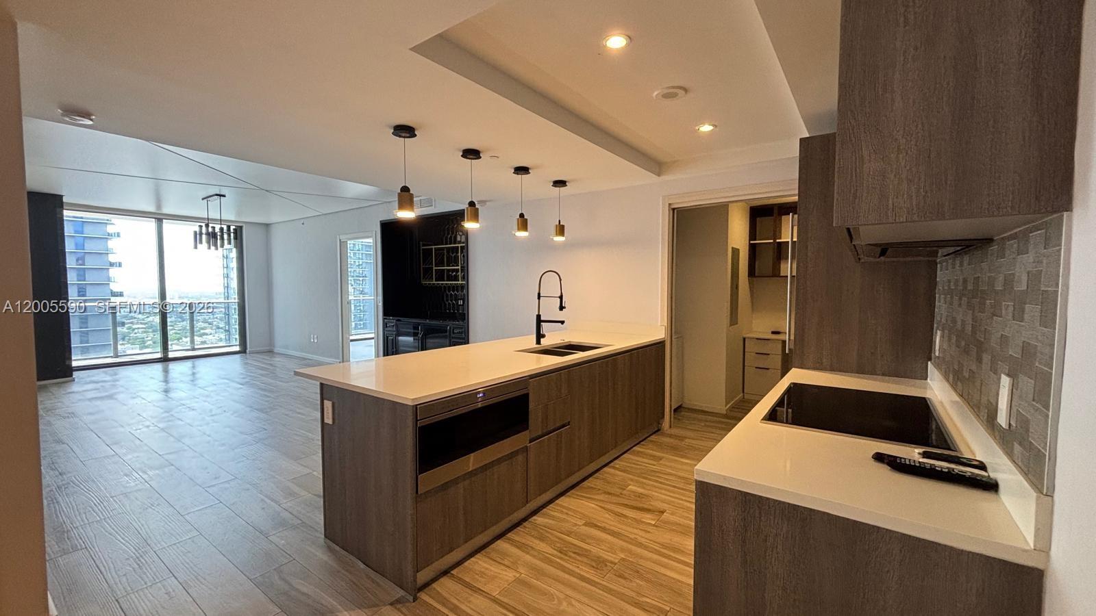 A modern kitchen features wood-toned cabinetry, white countertops, and a large island with pendant lighting — 801 S Miami Ave # 3510, Miami FL 33130, MIAMI, FL