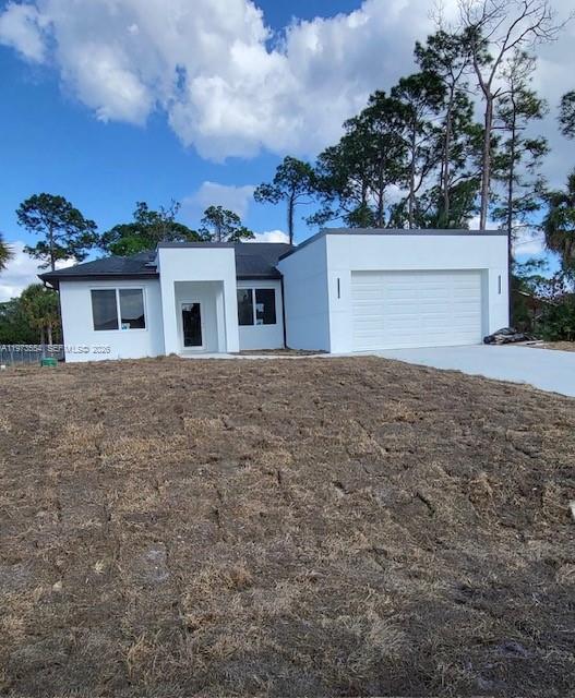 A modern white single-story house features a two-car garage and a newly laid sod lawn — 718 Robert Ave, Lehigh Acres FL 33936, LEHIGH ACRES, FL