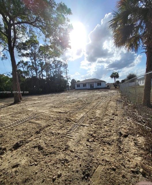 A large, cleared dirt lot with tire tracks leads toward a house in the distance — 718 Robert Ave, Lehigh Acres FL 33936, LEHIGH ACRES, FL