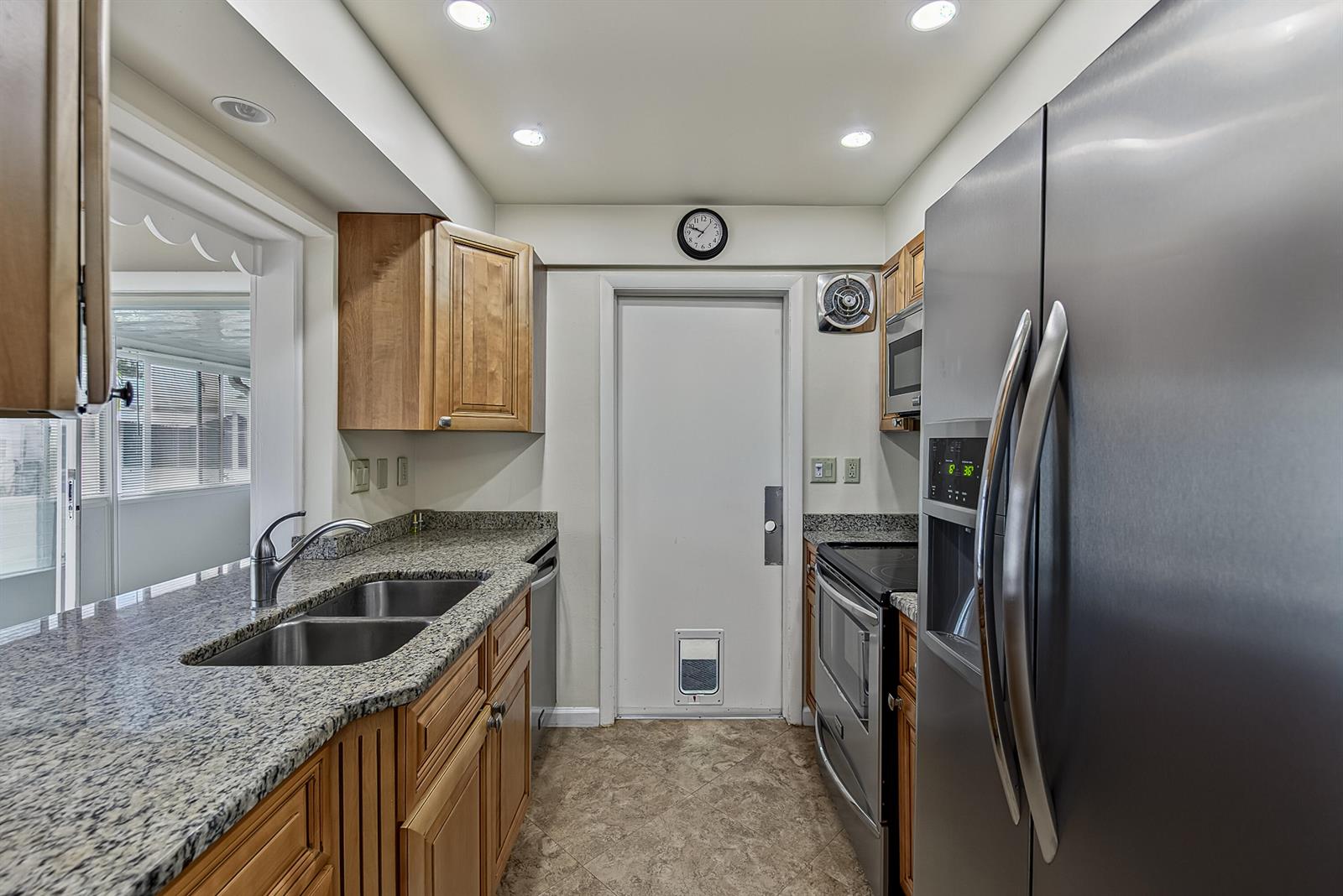 A kitchen features wood cabinets, granite countertops, stainless steel appliances, and a pet door — 2581 E Golf Boulevard, Pompano Beach FL 33064, POMPANO BEACH, FL
