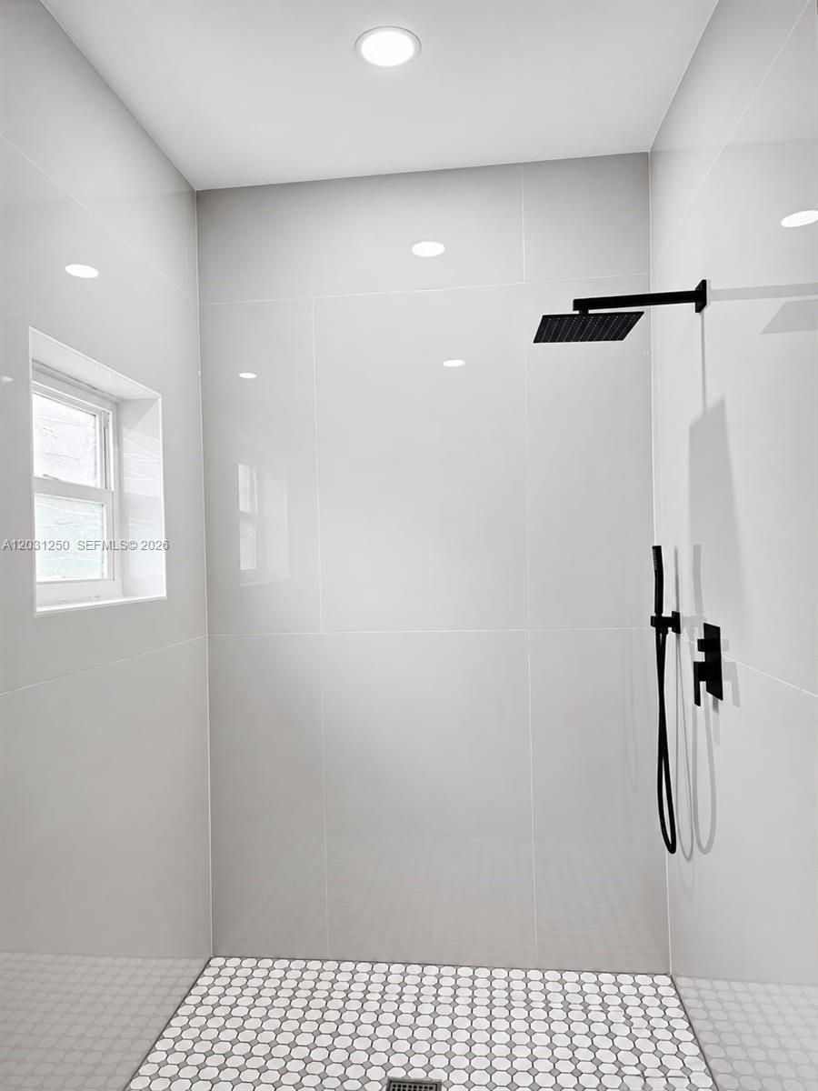 A walk-in shower features white wall tiles, a black rainfall showerhead, and a hexagonal tile floor — 907 21st St, West Palm Beach FL 33407, WEST PALM BEACH, FL