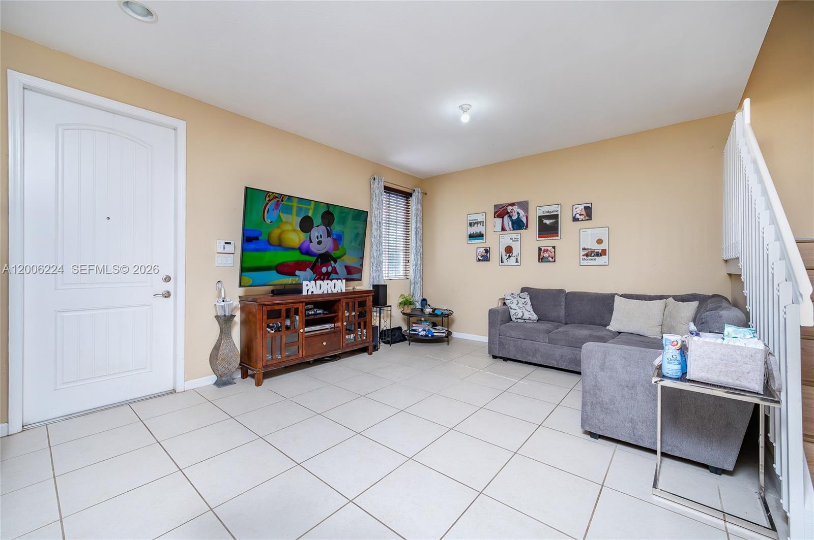 A living room features a grey sectional sofa, a television on a wooden console, and tile flooring — 27524 SW 140th Ave, Homestead FL 33032, HOMESTEAD, FL