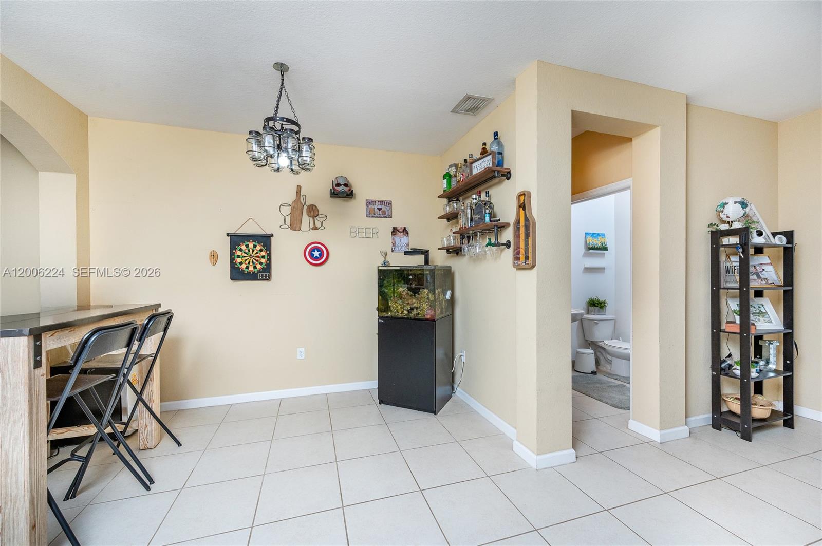 A room with a bar area, dartboard, fish tank, shelving, and an adjacent bathroom — 27524 SW 140th Ave, Homestead FL 33032, HOMESTEAD, FL