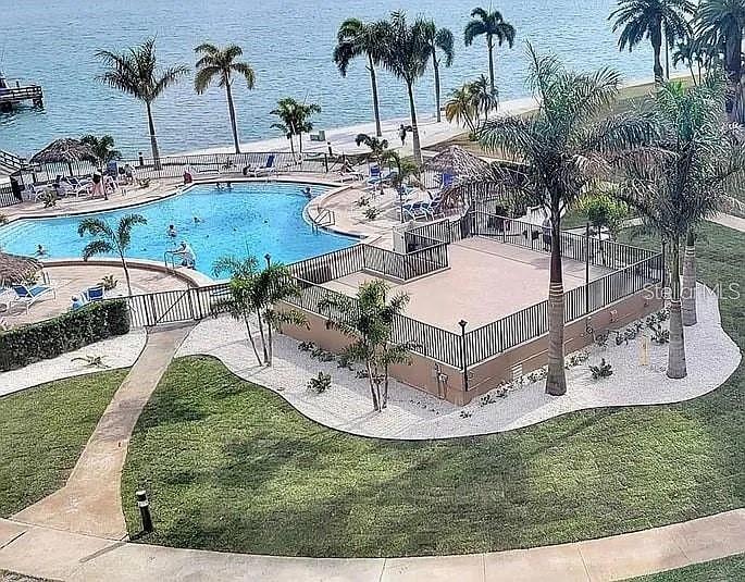 An elevated view shows a swimming pool, a fenced patio, and palm trees near water — 5108 BRITTANY DRIVE S UNIT 903, ST PETERSBURG, FL