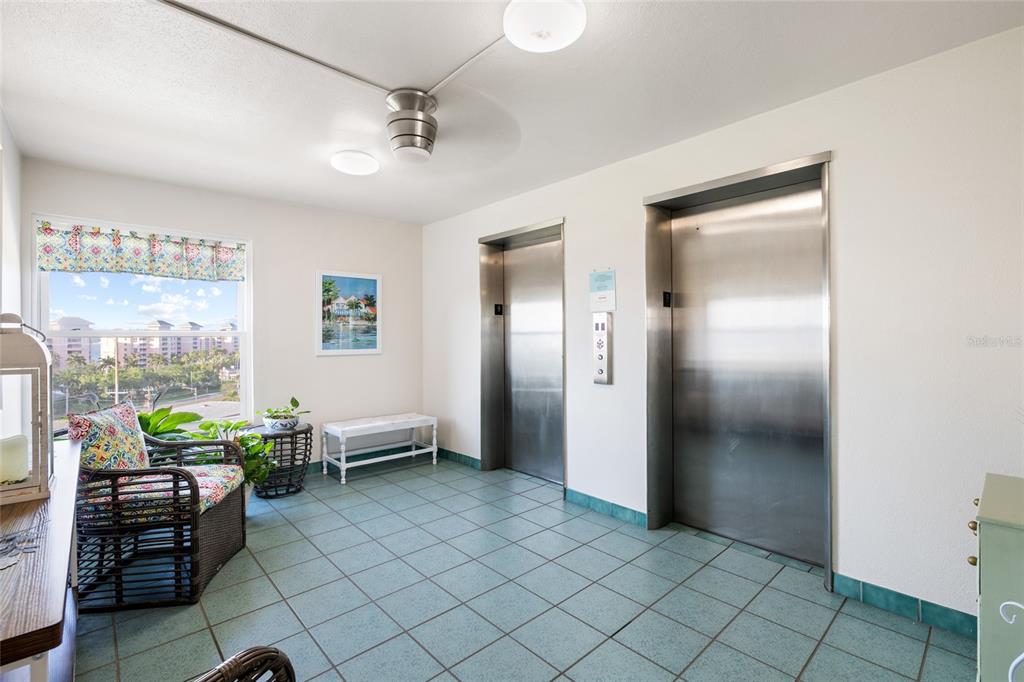 An elevator lobby with tile flooring, two metal elevator doors, and a window with seating — 5108 BRITTANY DRIVE S UNIT 903, ST PETERSBURG, FL