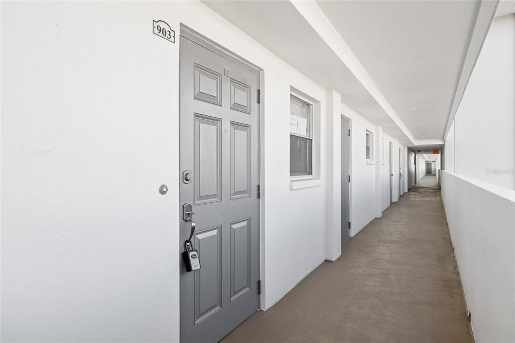A gray door labeled 903 opens onto an outdoor apartment building walkway — 5108 BRITTANY DRIVE S UNIT 903, ST PETERSBURG, FL