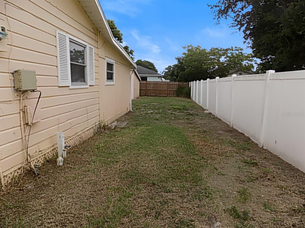 A side yard features a light-colored house exterior, a white vinyl fence, and grass — 4610 SLOAN AVENUE, SARASOTA, FL
