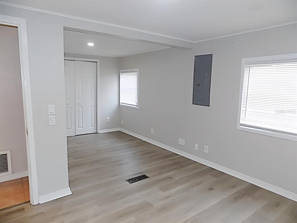 A room with light gray walls, wood-look flooring, two windows, and a closet with white doors — 4610 SLOAN AVENUE, SARASOTA, FL
