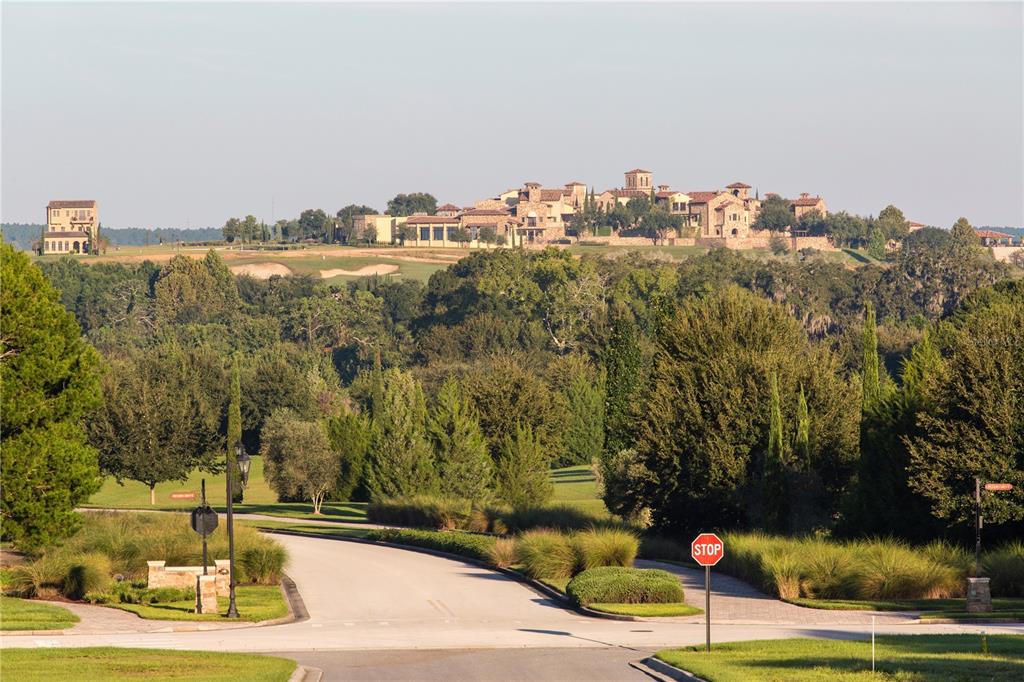 A paved road leads toward a large stone estate situated on a distant grassy hill — 15393 APENNINE WAY, MONTVERDE, FL