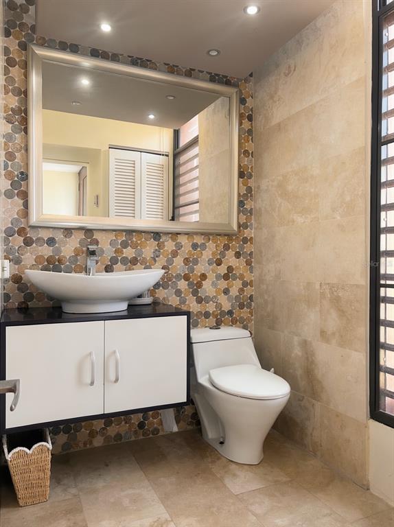 A bathroom features a vessel sink on a white vanity, a toilet, and mosaic tile walls — 170 PALMAS DRIVE UNIT C3, HUMACAO, PR