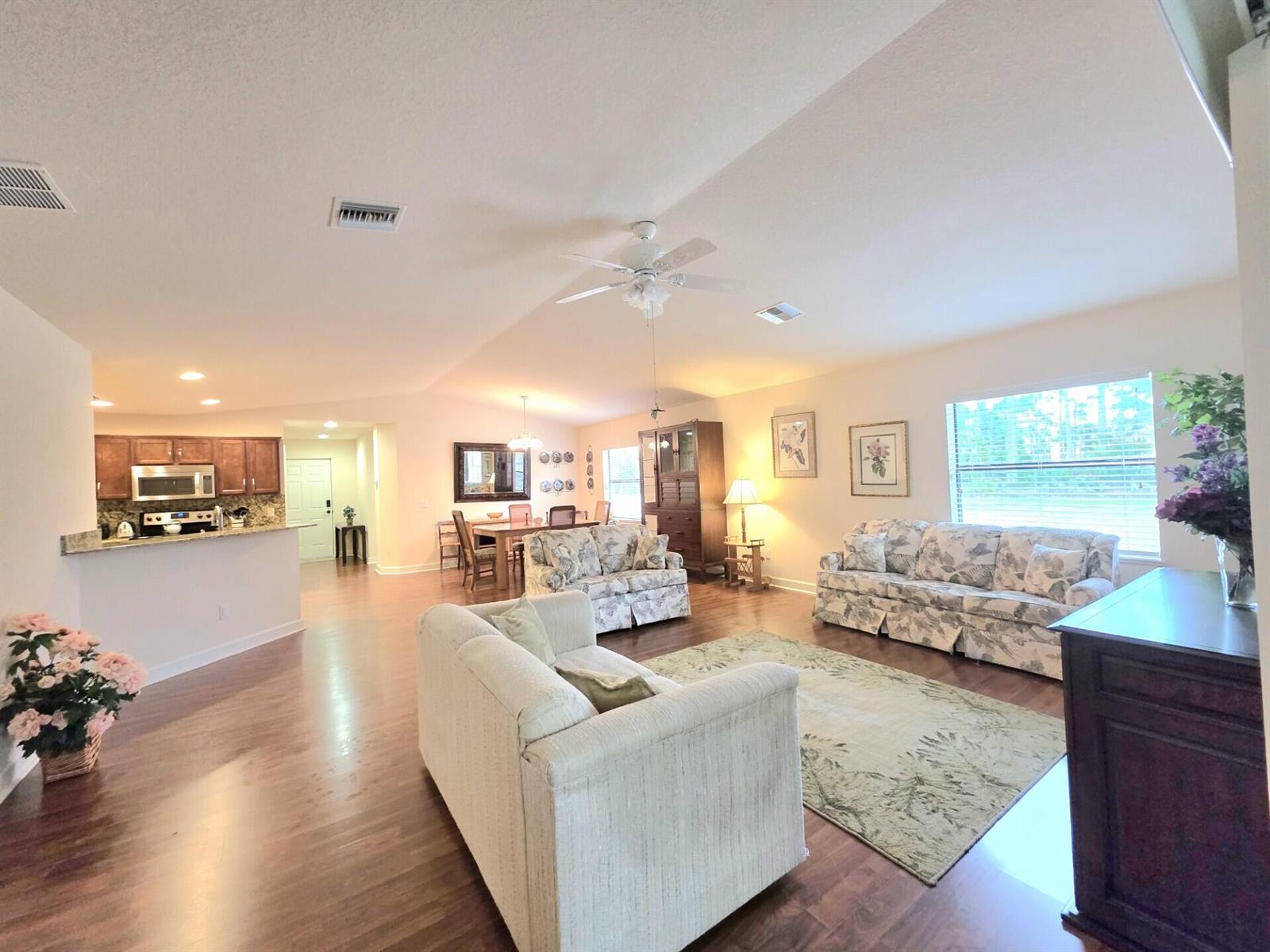 A spacious open-concept living and dining area with wood flooring and a vaulted ceiling — 17 San Felipe, Fort Pierce FL 34951, FORT PIERCE, FL