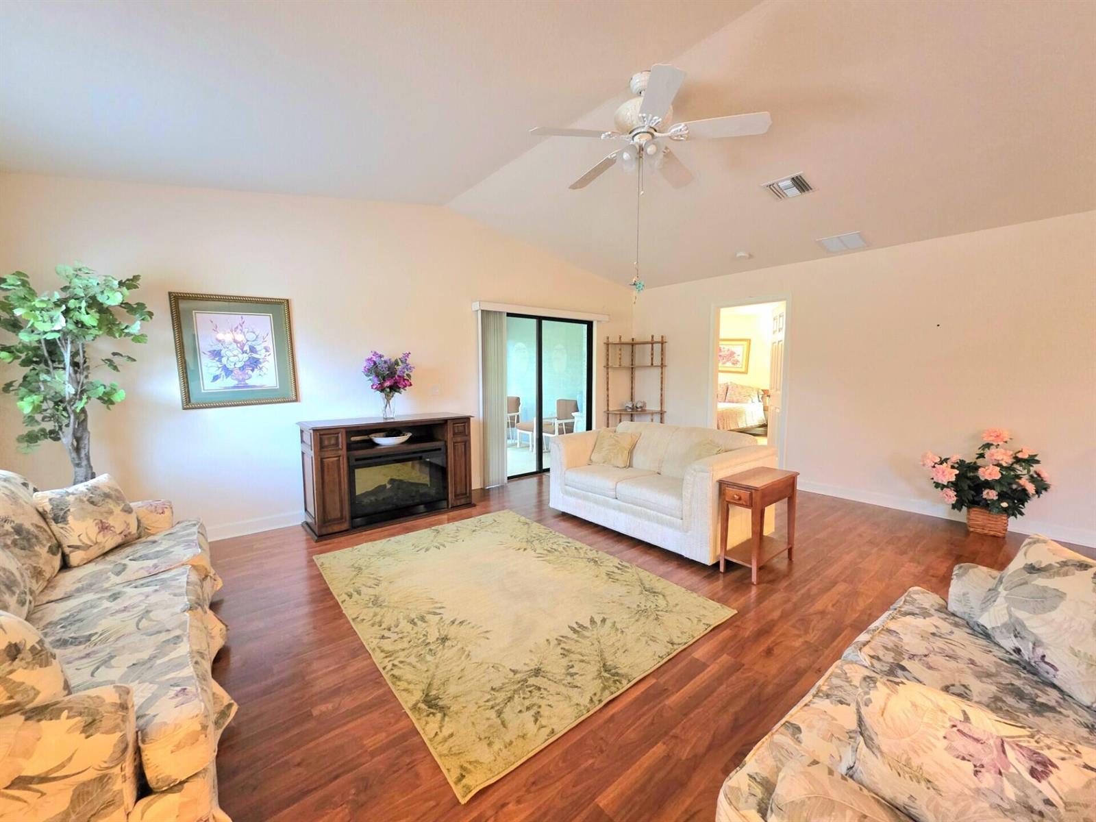 A living room with wood flooring, floral sofas, a fireplace console, and a ceiling fan — 17 San Felipe, Fort Pierce FL 34951, FORT PIERCE, FL