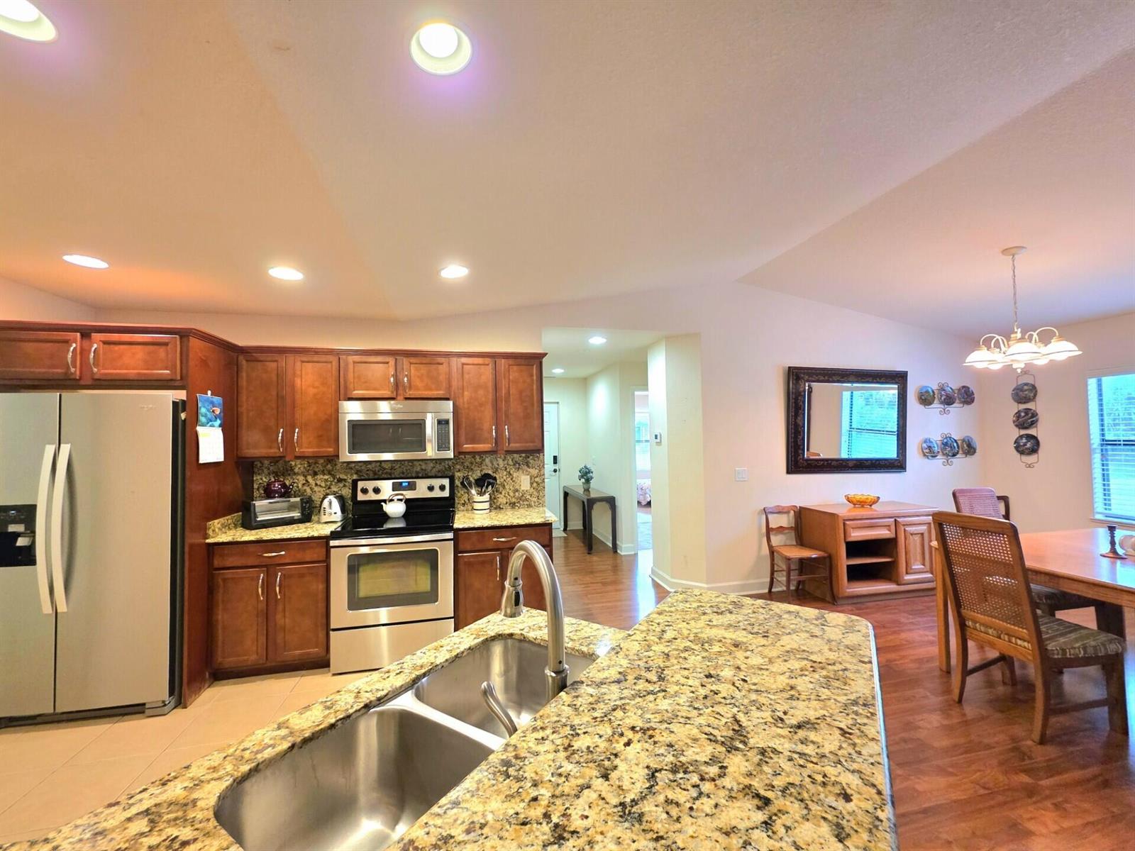 A kitchen with granite countertops, stainless steel appliances, and wood cabinets overlooks a dining area — 17 San Felipe, Fort Pierce FL 34951, FORT PIERCE, FL