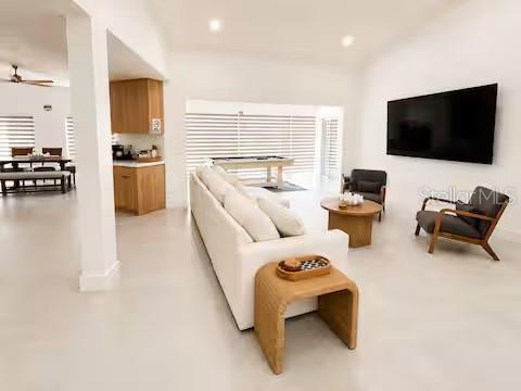 A bright, open-concept living room features a white sofa, wood furniture, and a wall-mounted television — 4760 CAMPHOR AVENUE, SARASOTA, FL