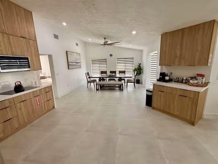 A modern kitchen and dining area feature light wood cabinetry and large floor tiles — 4760 CAMPHOR AVENUE, SARASOTA, FL