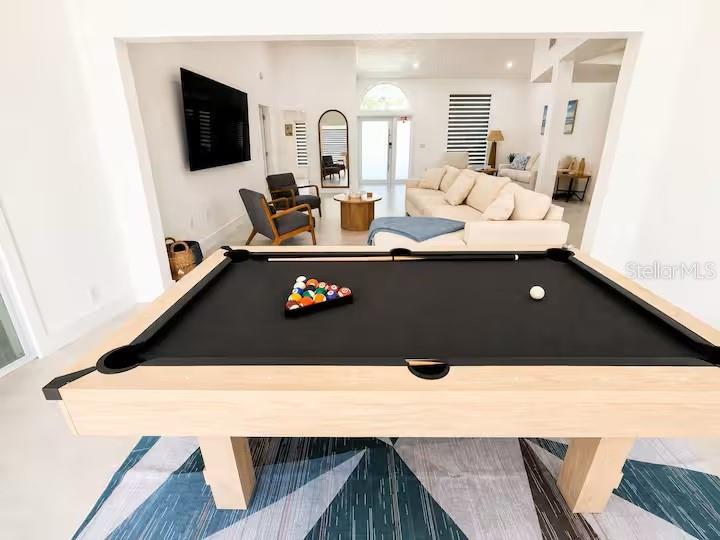 A pool table sits in the foreground of a living room with a sectional sofa — 4760 CAMPHOR AVENUE, SARASOTA, FL