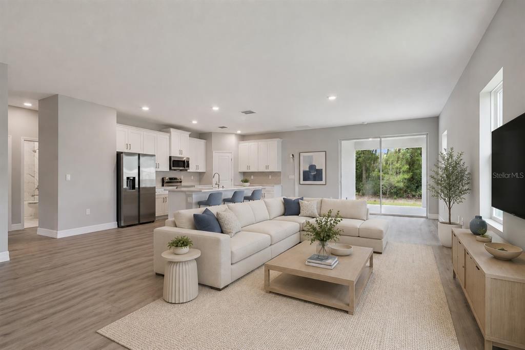 A modern open-concept living room and kitchen featuring light wood floors and white cabinetry — 3694 SW 131ST STREET, OCALA, FL