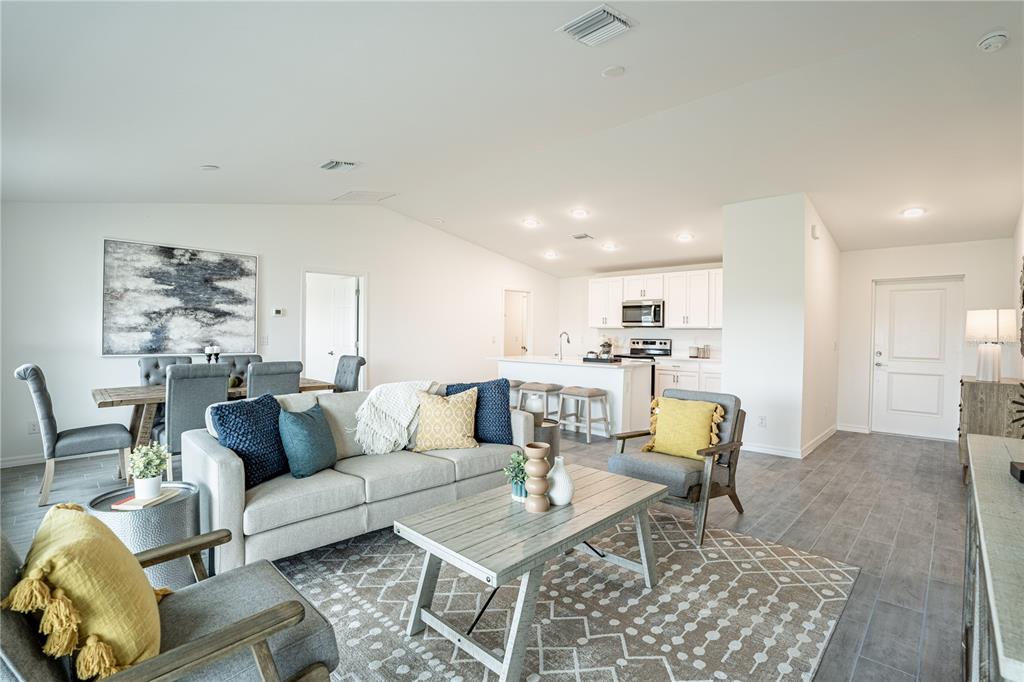 An open-concept living and dining area features a kitchen with white cabinets and tile flooring — 2027 BROAD RANCH DRIVE, PORT CHARLOTTE, FL