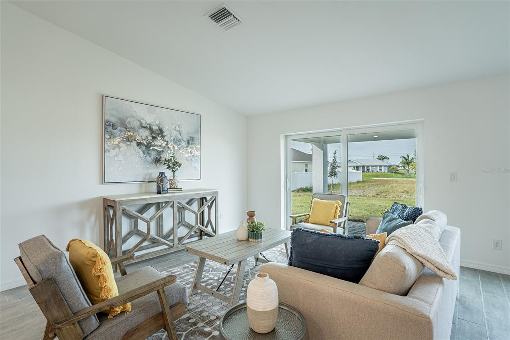 A living room features a sofa, armchairs, a coffee table, and a sliding glass door — 2027 BROAD RANCH DRIVE, PORT CHARLOTTE, FL