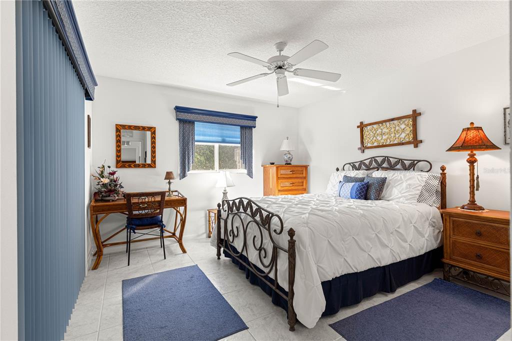 A bedroom features a white bed, a wooden desk, a ceiling fan, and tiled floors — 5292 NW 19TH PLACE, OCALA, FL