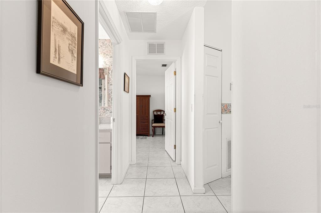 A hallway with white tile flooring leads to a bathroom and a bedroom beyond — 5292 NW 19TH PLACE, OCALA, FL