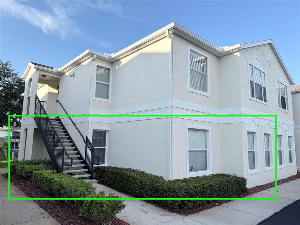Exterior view of a two-story apartment building with a staircase and landscaped shrubbery — 8844 GRAND PALMS CIRCLE UNIT A, KISSIMMEE, FL
