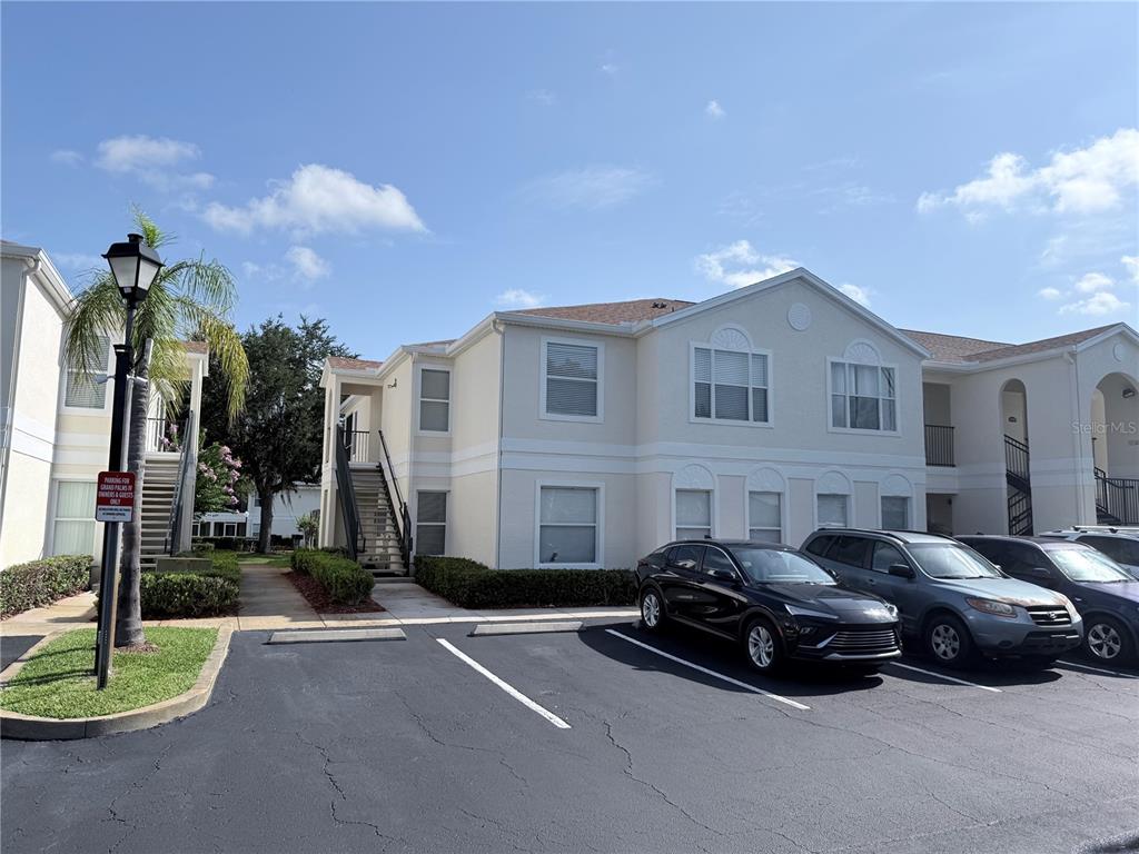 A two-story apartment building with beige stucco siding and a parking lot in front — 8844 GRAND PALMS CIRCLE UNIT A, KISSIMMEE, FL