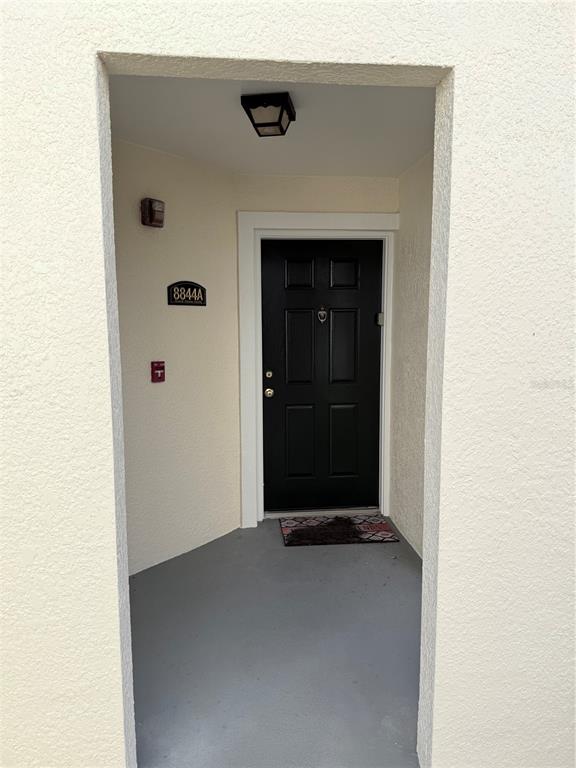 A black front door is set within a recessed entryway with light-colored stucco walls — 8844 GRAND PALMS CIRCLE UNIT A, KISSIMMEE, FL